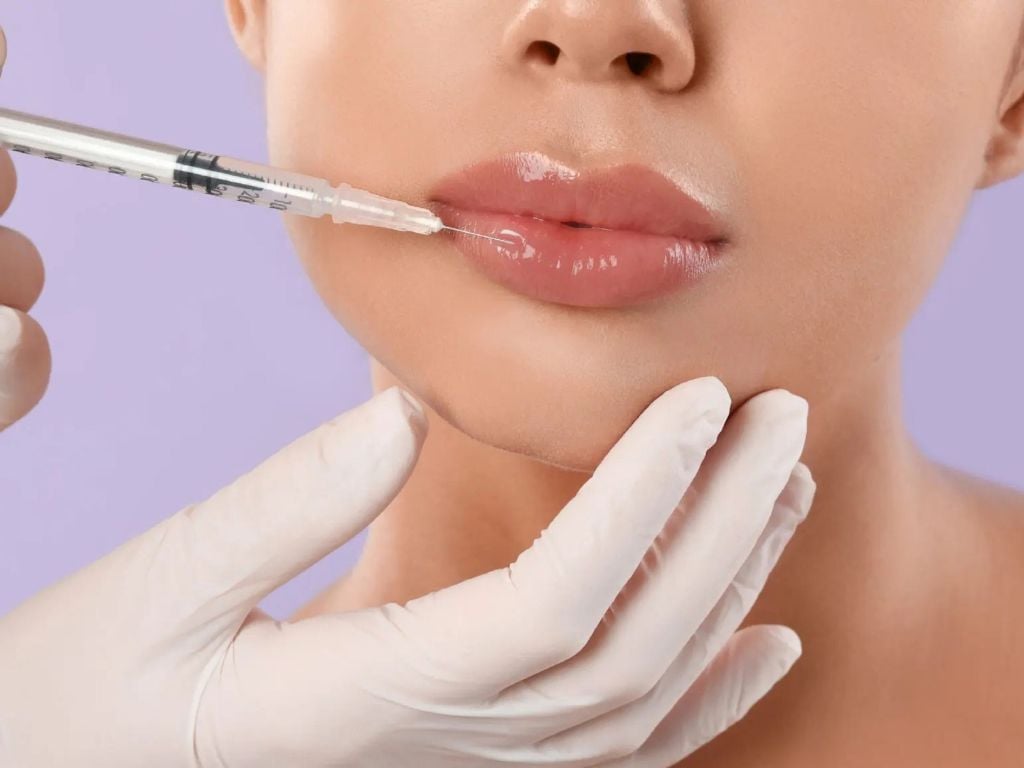 Doctor in black gloves performing a lip filler injection with hyaluronic acid