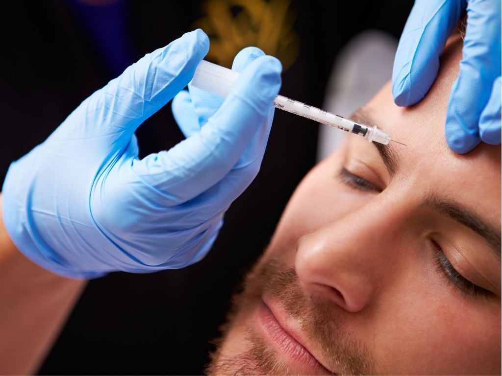 Man receiving an injectable treatment between the eyebrows for expression lines at an aesthetic medicine clinic