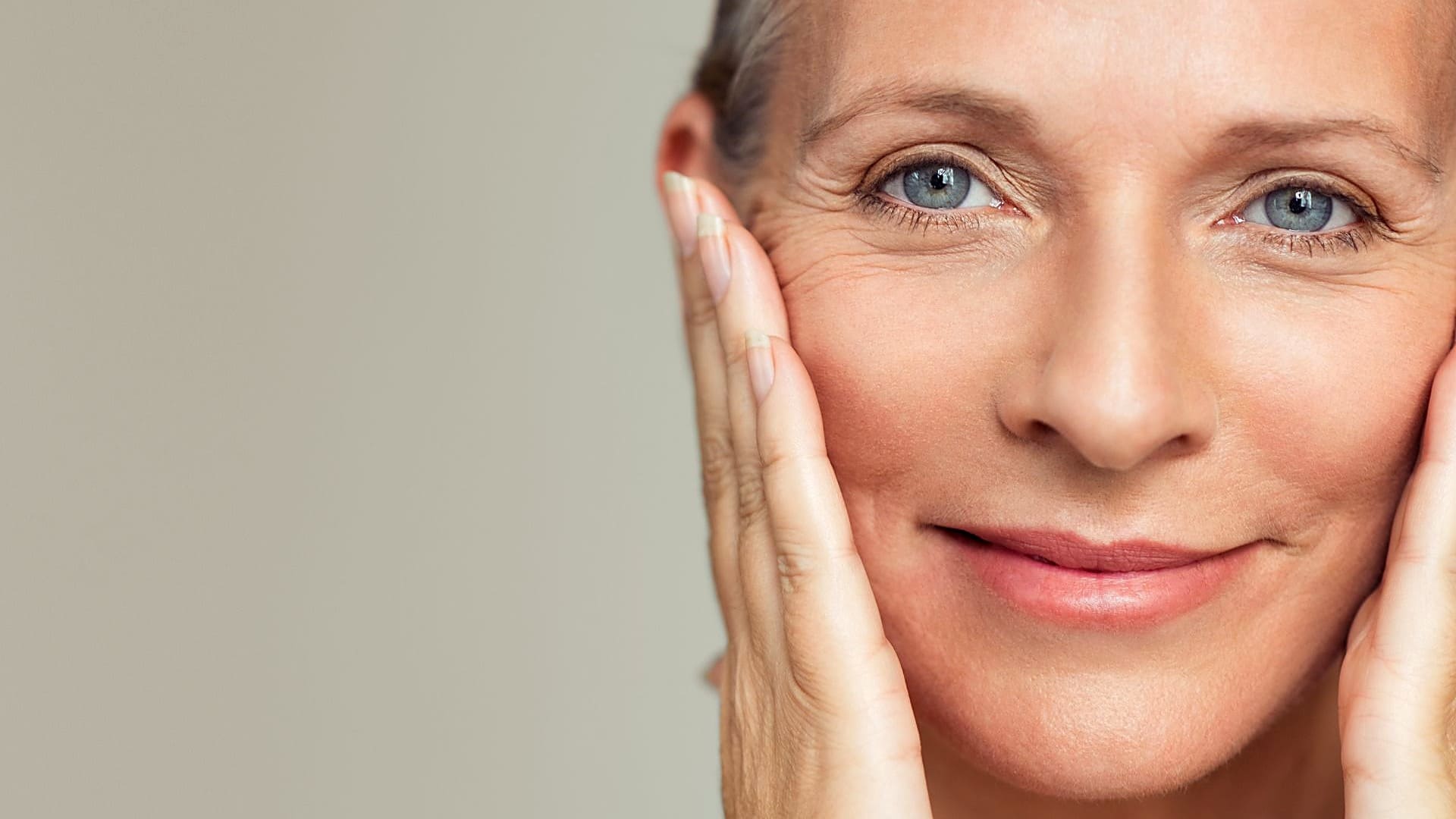 Menopausal woman touching her face, with fine lines visible around the eyes