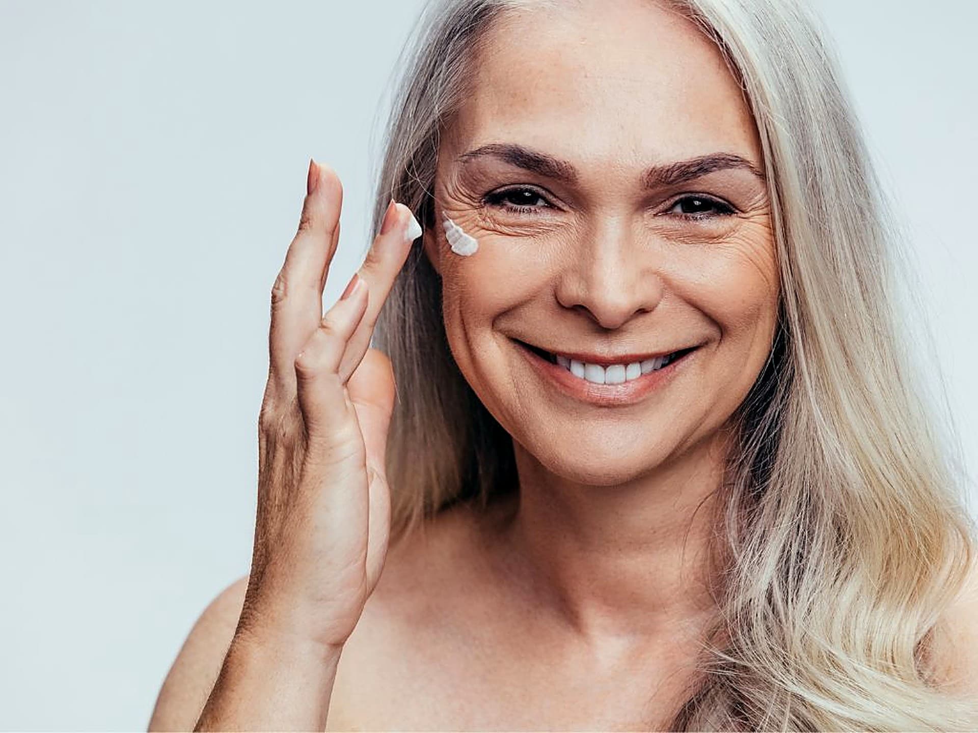 Older woman applying facial cream as part of her daily skincare routine