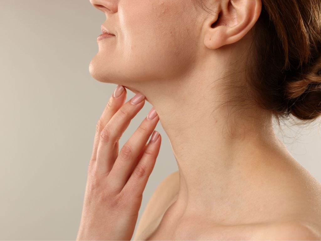 Woman touching her neck in an article about neck ageing